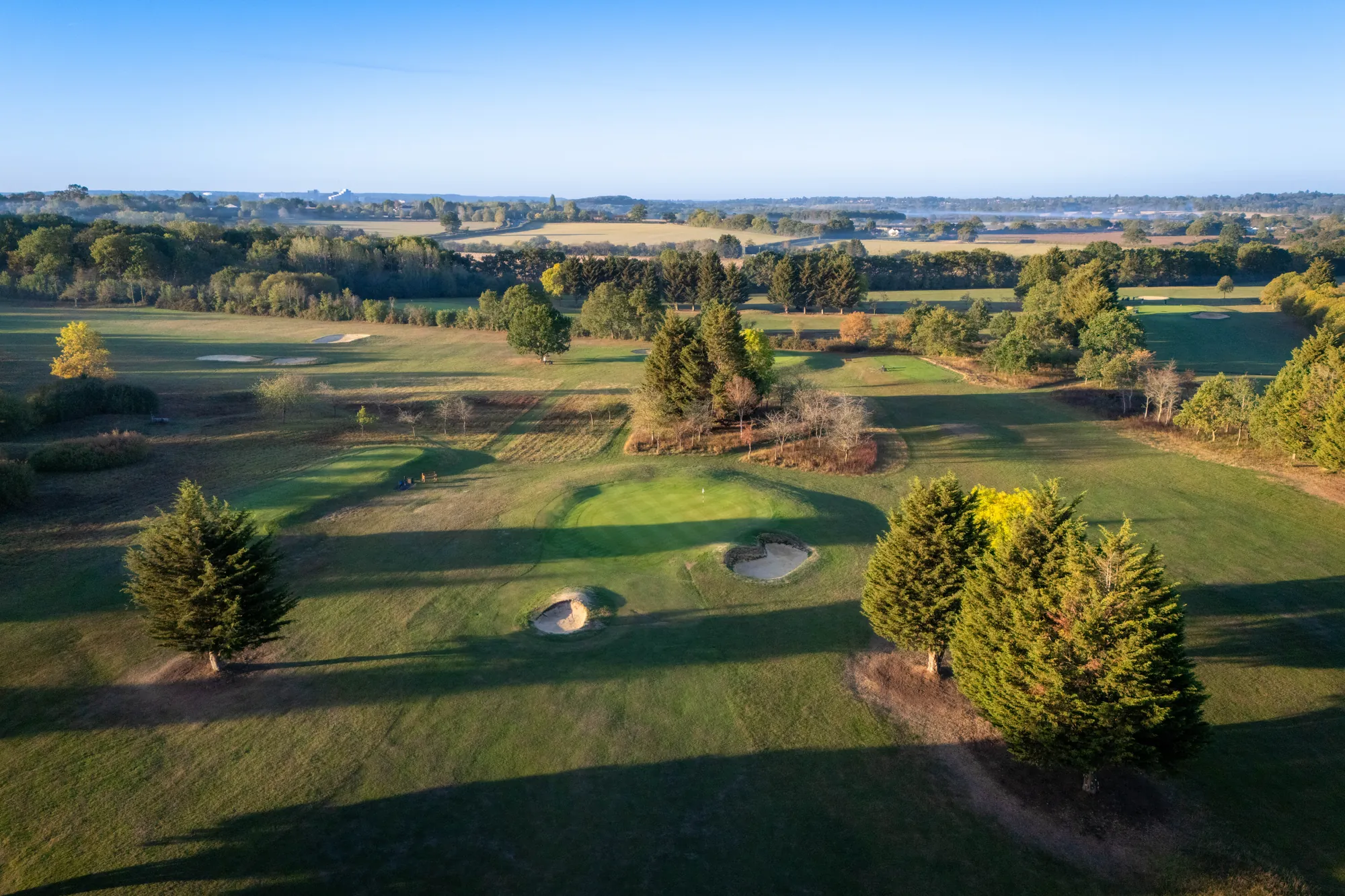 Bird Hills from the air at first light, a green ringed by trees