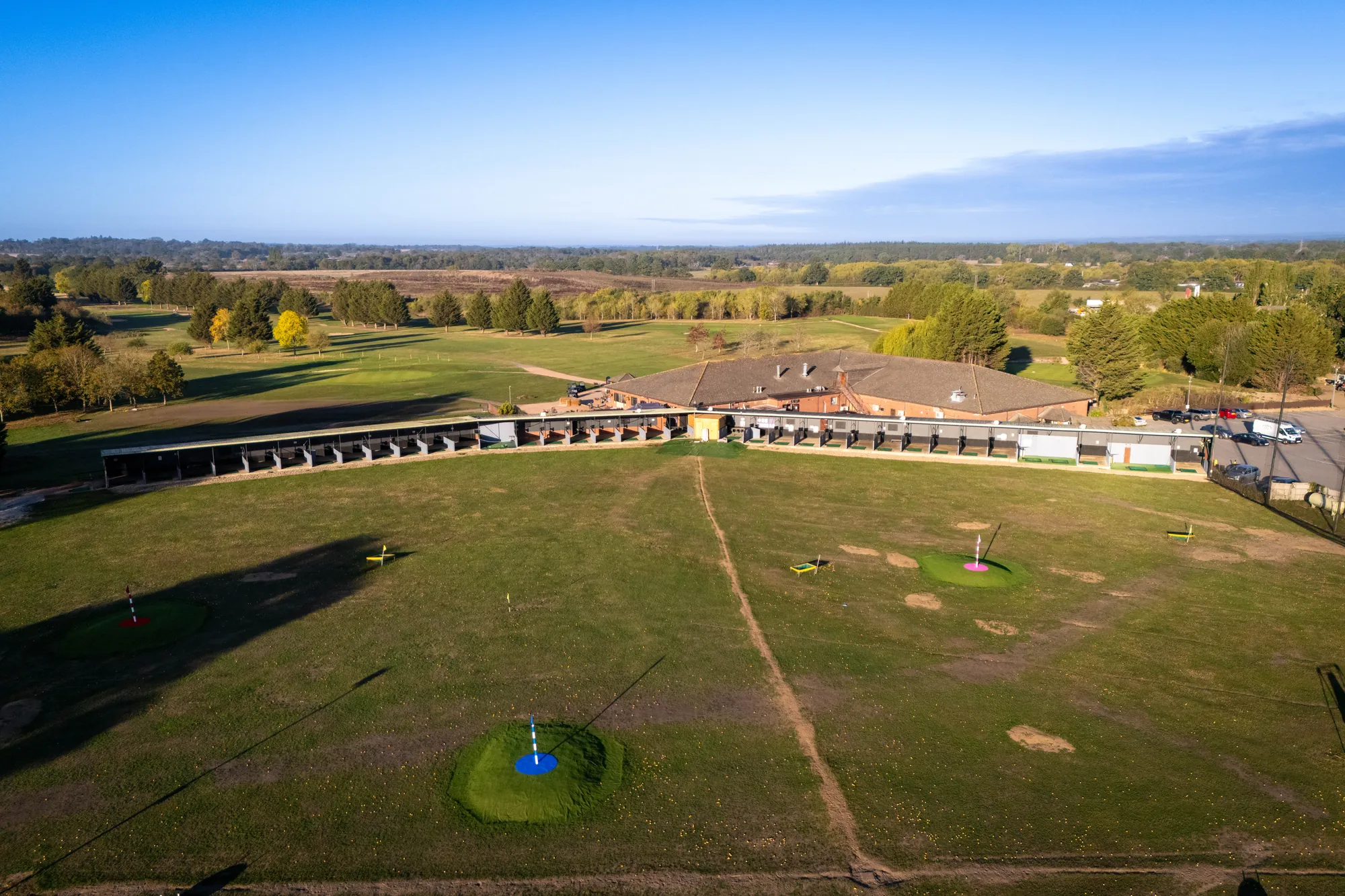 The clubhouse and driving range from the air, the course stretching away behind
