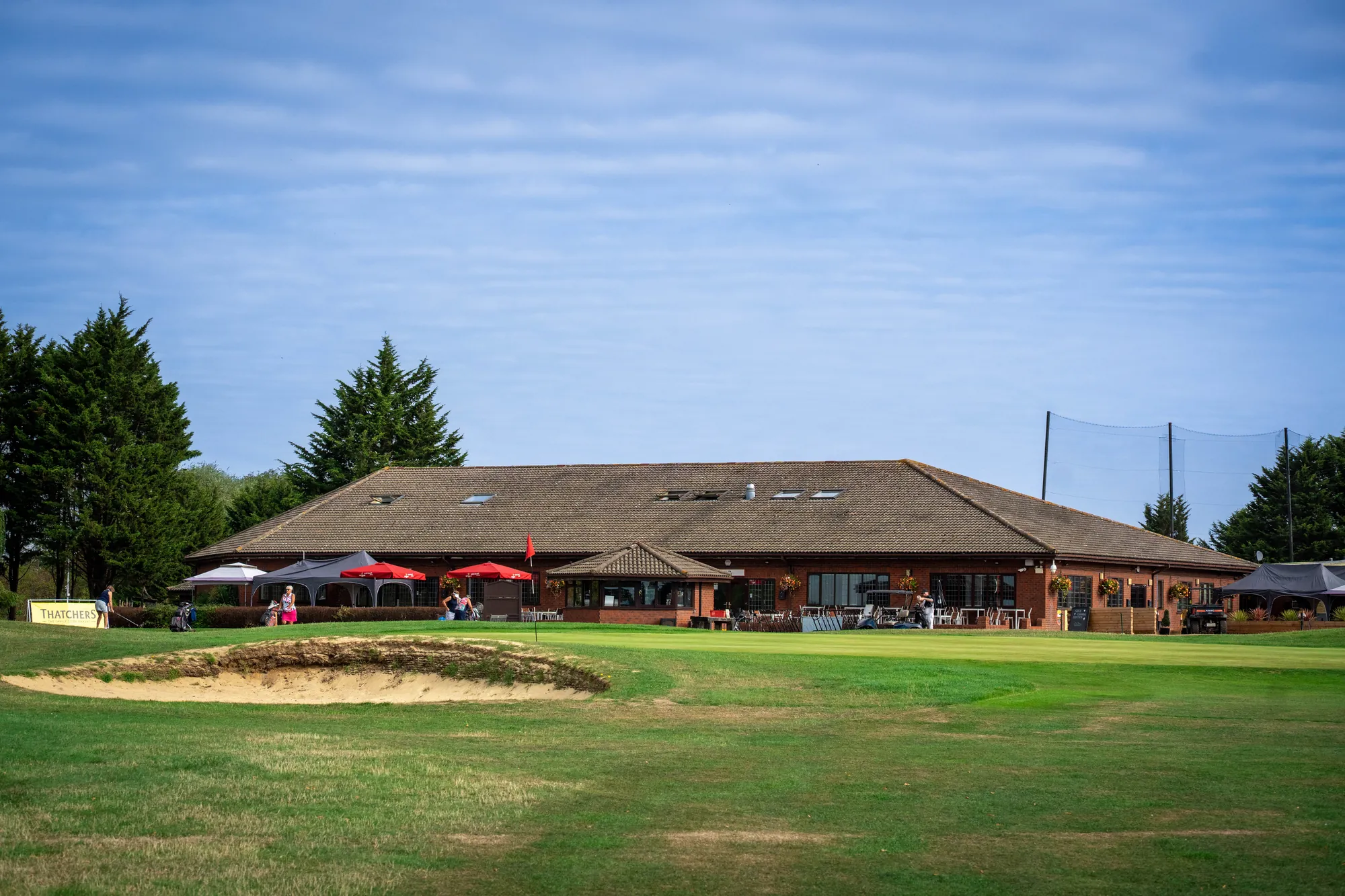 The clubhouse seen across the course, a bunker in the foreground