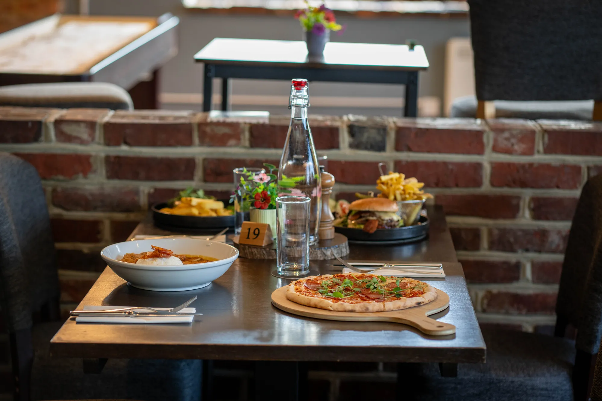 A restaurant table laid with pizza, curry, burgers and drinks
