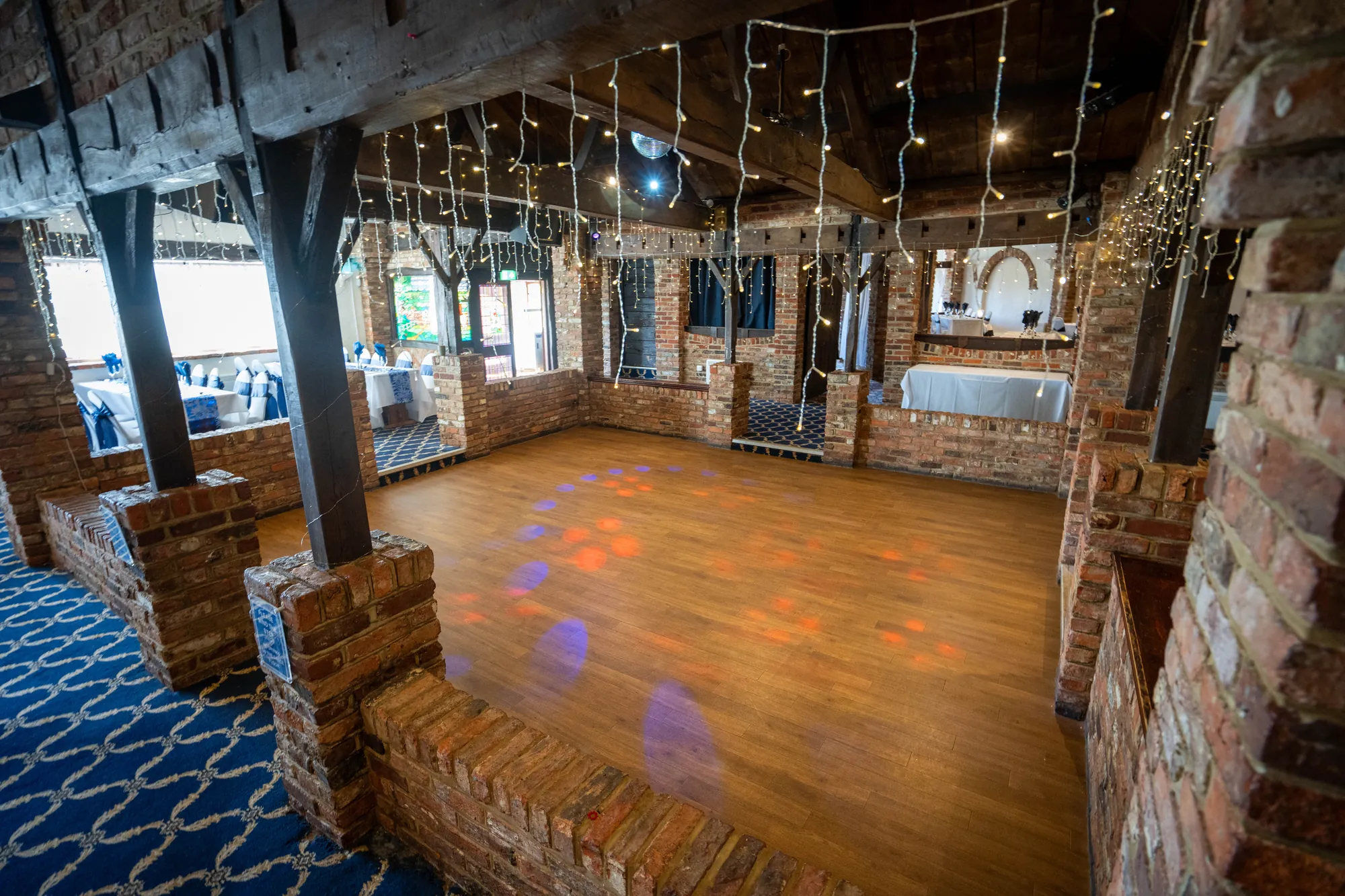 The dance floor in the function room, lit with coloured lights and fairy lights on the beams