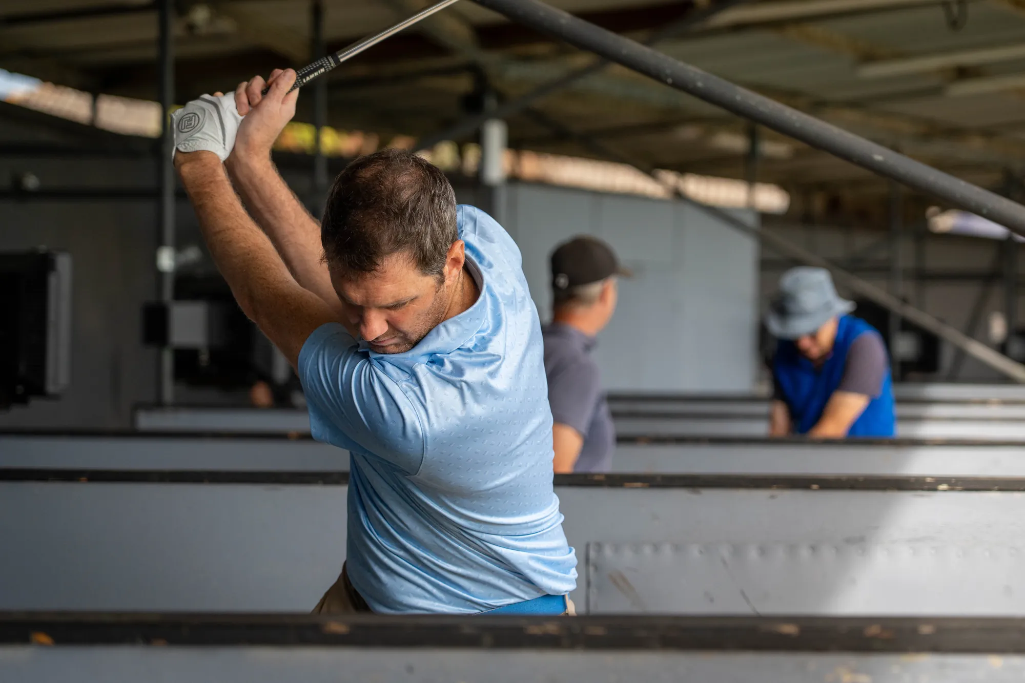 A golfer at the top of his backswing in a range bay